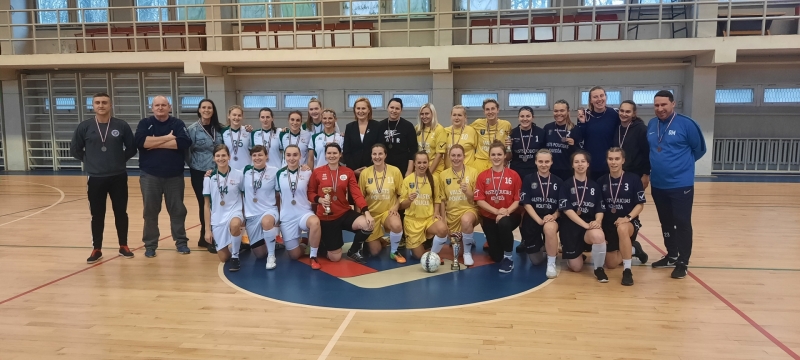Cilvēki krāsainos formas tērpos ar medaļām sporta zālē