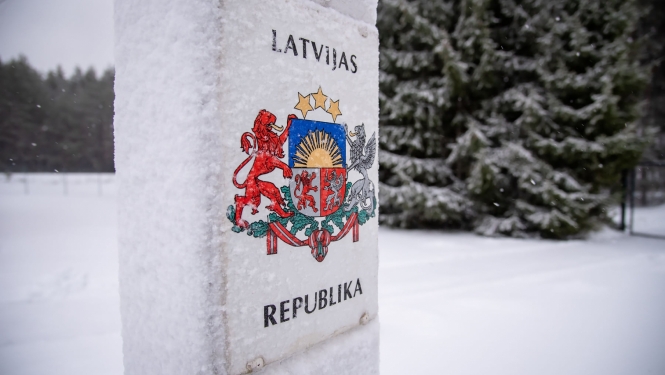 Robežstabs ziemā, fonā mežs