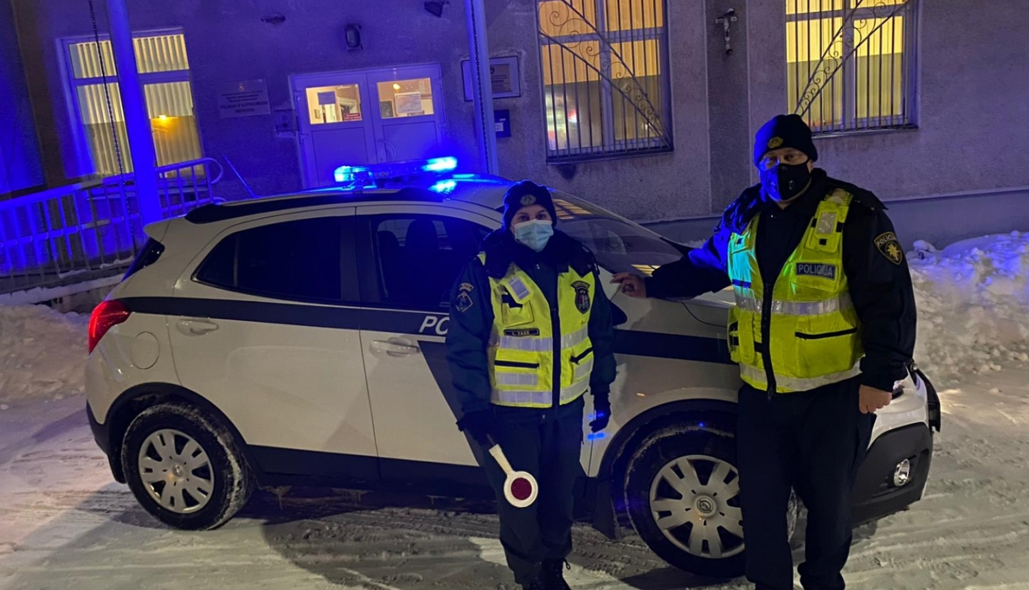 robežsargs un policists stāv pie policijas mašīnas