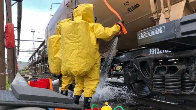 ugunsdzēsēji dzeltenos aizsargtērpos pie kravas mašīnas