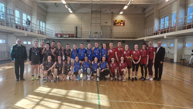 komandas stāv zālē ar medaļām