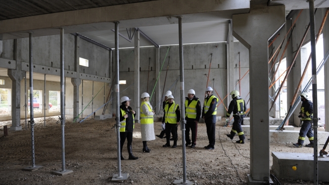 Ēkas iekšienē konstrukcijas un cilvēki ar zaļām vestēm