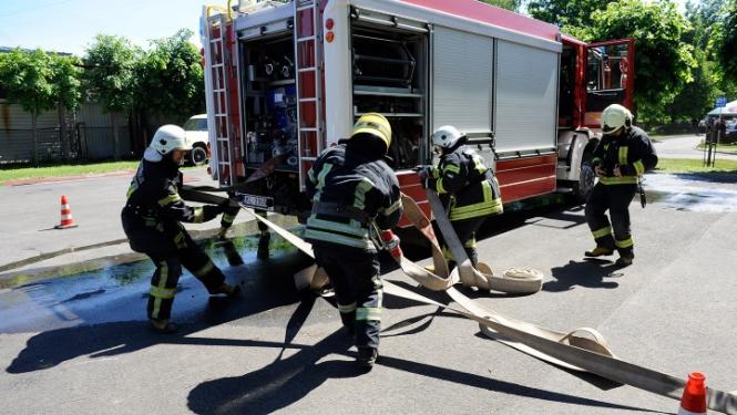 Ugunsdzēsēji pie ugunsdzēsēju automašīnas