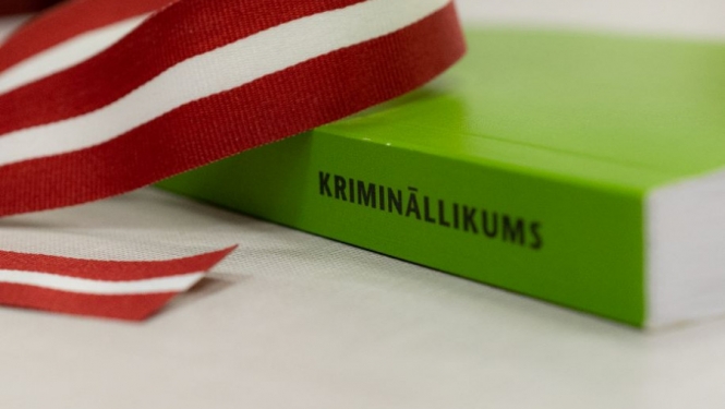 Zaļa grāmata uz galda ar Latvijas karoga lentīti