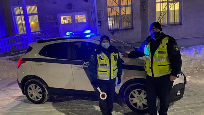 robežsargs un policists stāv pie policijas mašīnas
