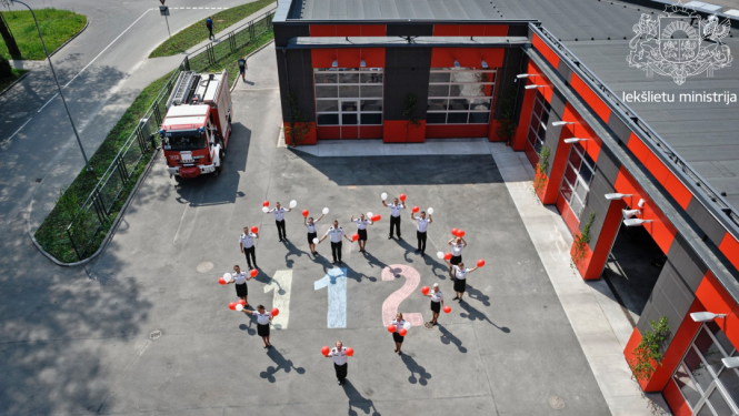 Ugunsdzēsēju depo un ugunsdzēsēji sadevušies rokās, veidojot sirds formu