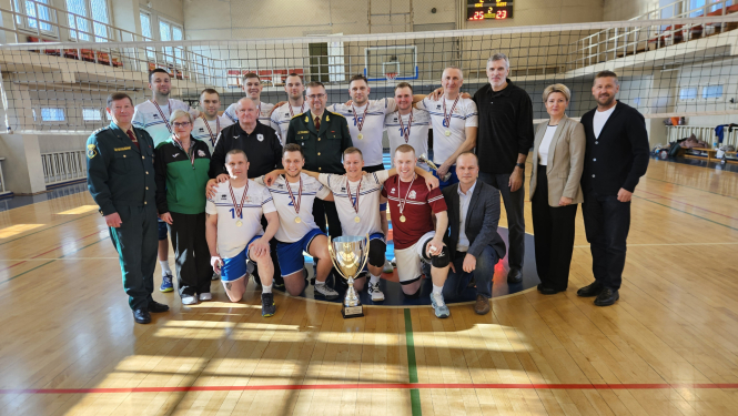 Sportisti ar medaļām stāv sporta zālē