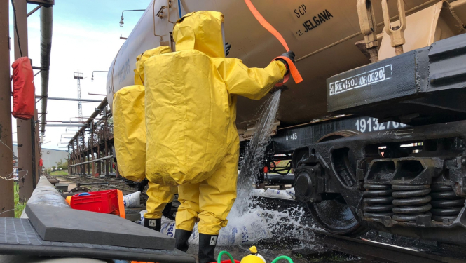 ugunsdzēsēji dzeltenos aizsargtērpos pie kravas mašīnas