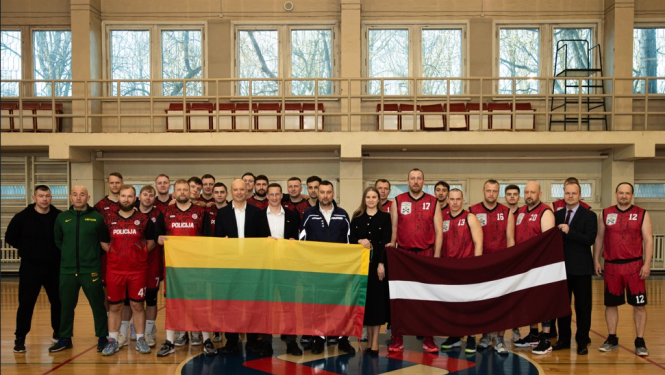 Komandas stāv ar Lietuvas un Latvijas karogu zālē