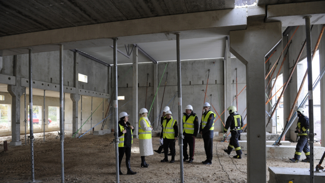 Ēkas iekšienē konstrukcijas un cilvēki ar zaļām vestēm