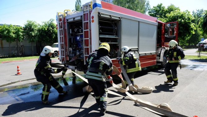 Ugunsdzēsēji pie ugunsdzēsēju automašīnas