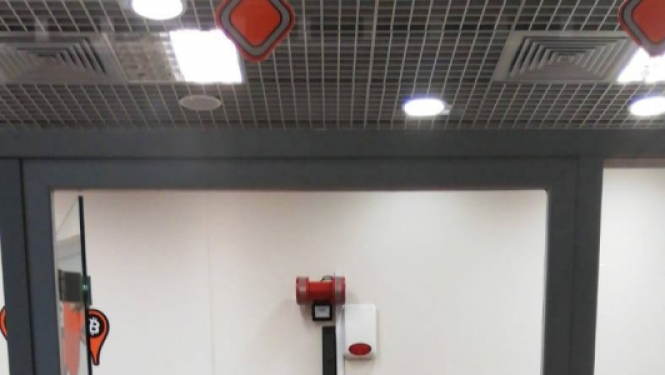 bitkoinu klubs ar lielu oranžu B burtu uz dienas un raibu paklāju uz grīdas