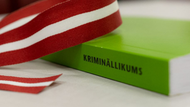 Zaļa grāmata uz galda ar Latvijas karoga lentīti