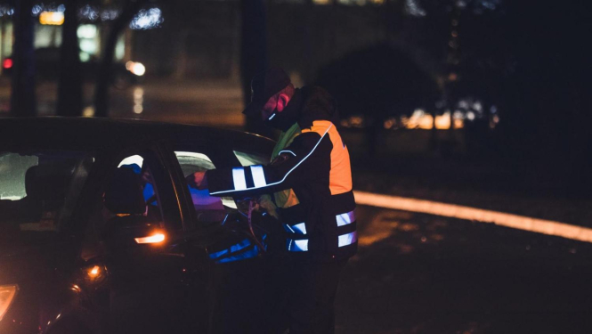 policists pārbauda apliecinājumu automašīnas vadītājam