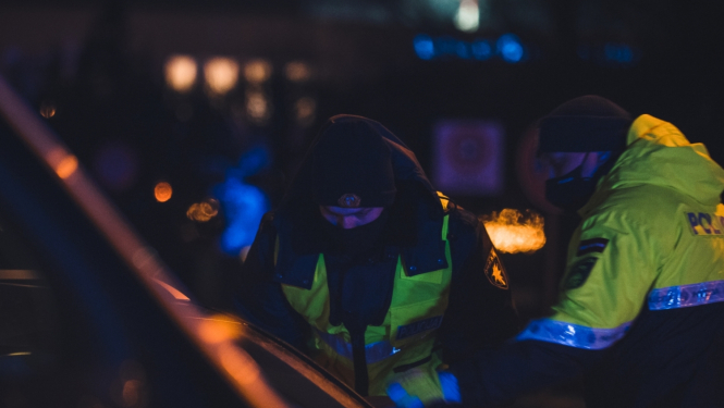 robežsargs un policists noliekušies pie mašīnas