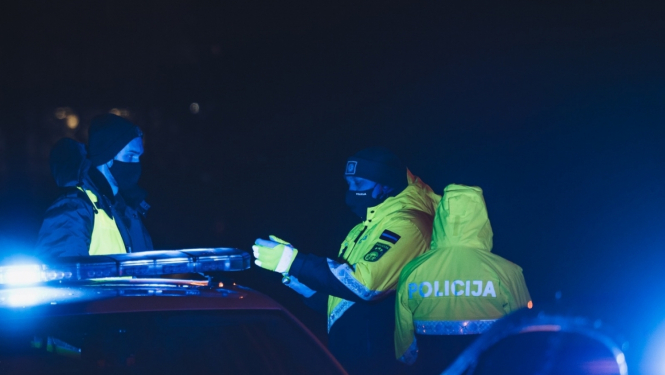 trīs policisti pie mašīnas naktī