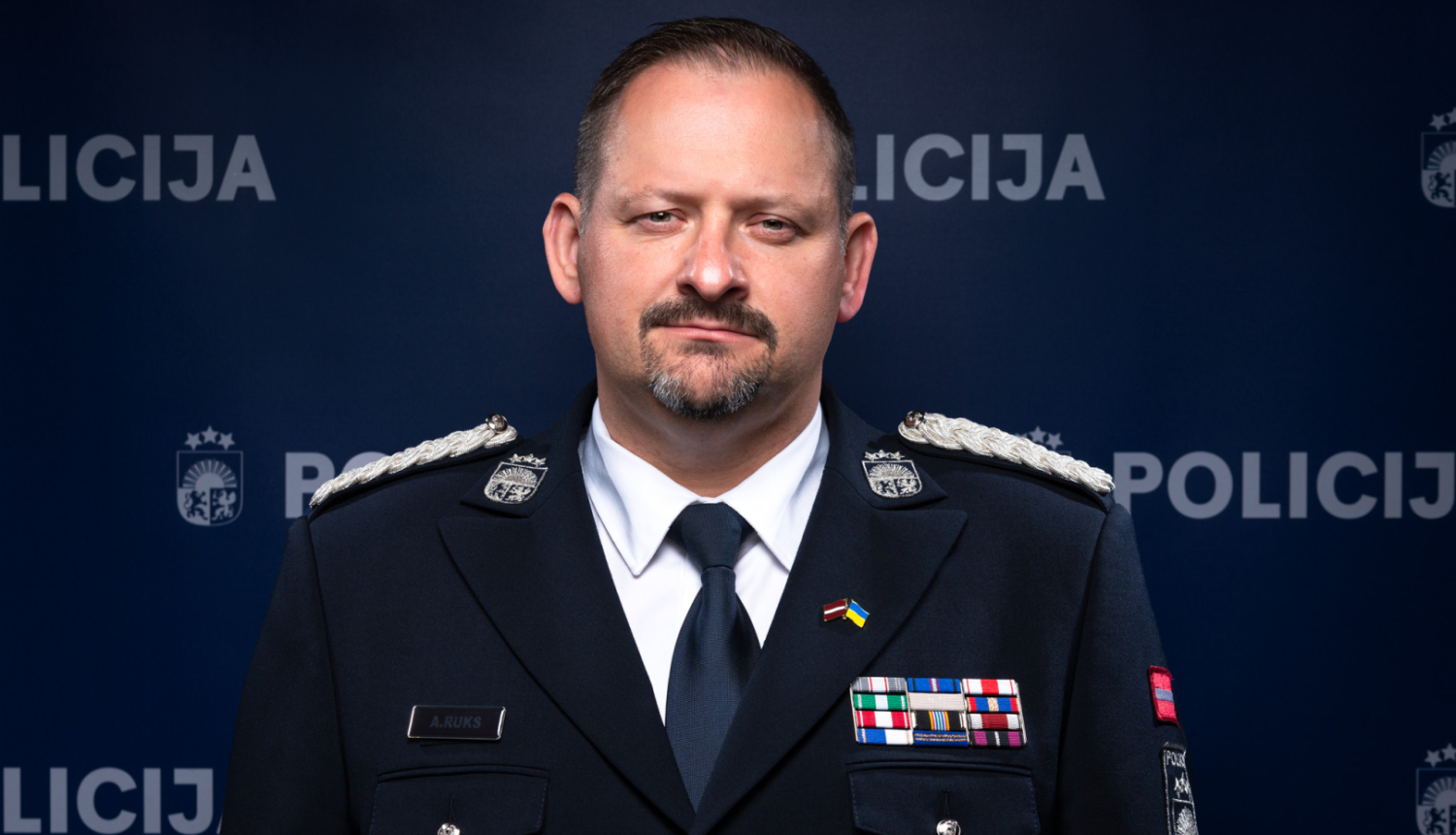 Policijas priekšnieks stāv pie Policijas banera