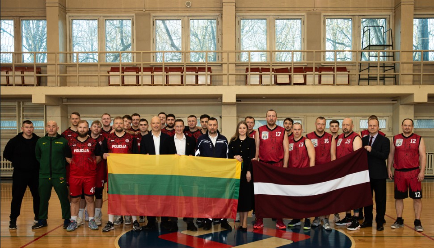Komandas stāv ar Lietuvas un Latvijas karogu zālē