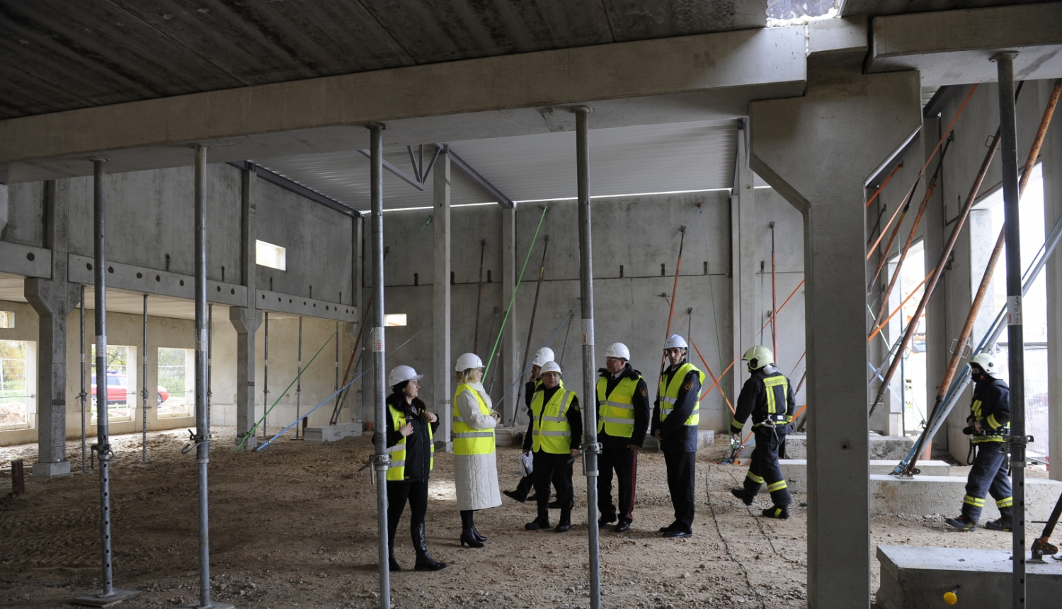 Ēkas iekšienē konstrukcijas un cilvēki ar zaļām vestēm