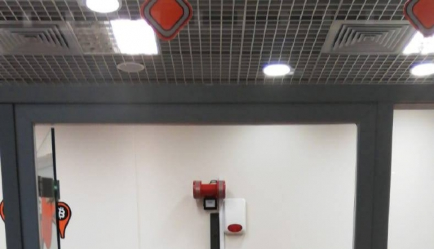 bitkoinu klubs ar lielu oranžu B burtu uz dienas un raibu paklāju uz grīdas