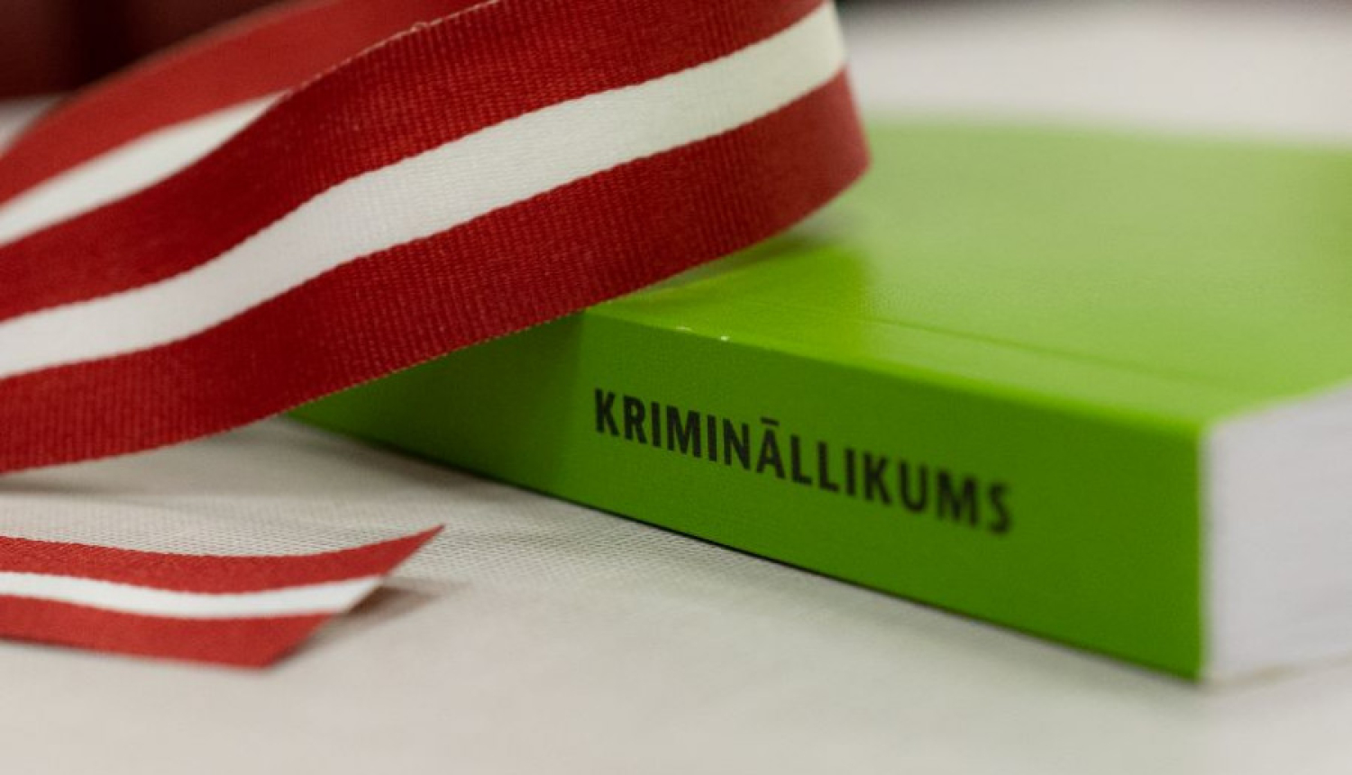 Zaļa grāmata uz galda ar Latvijas karoga lentīti