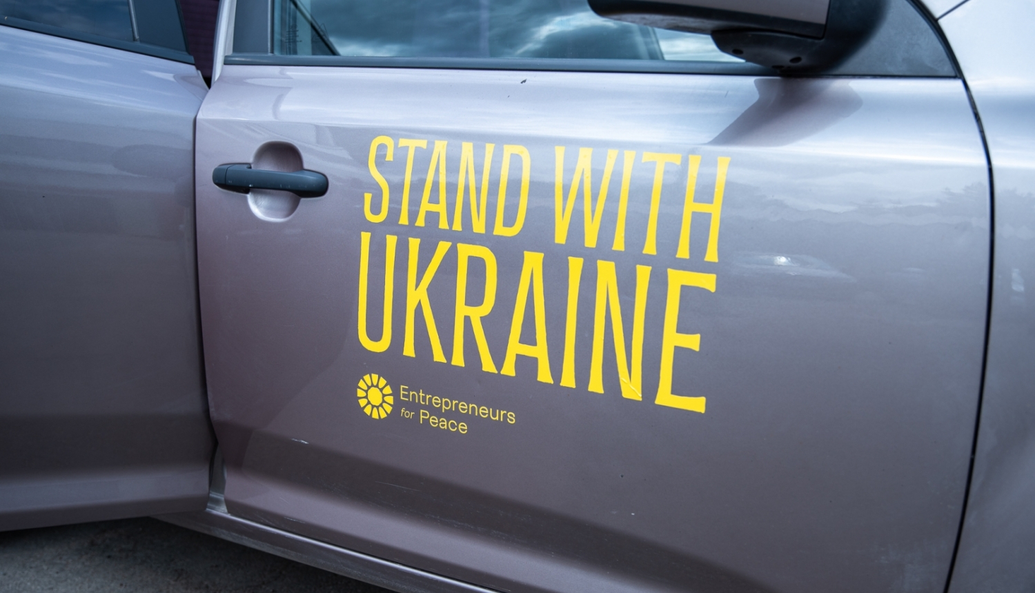 pelēks auto ar dzeltenu uzrakstu stand with UKRAINE
