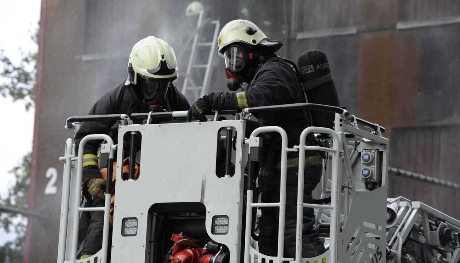 divi ugunsdzēsēji uz paceļamām kāpnēm