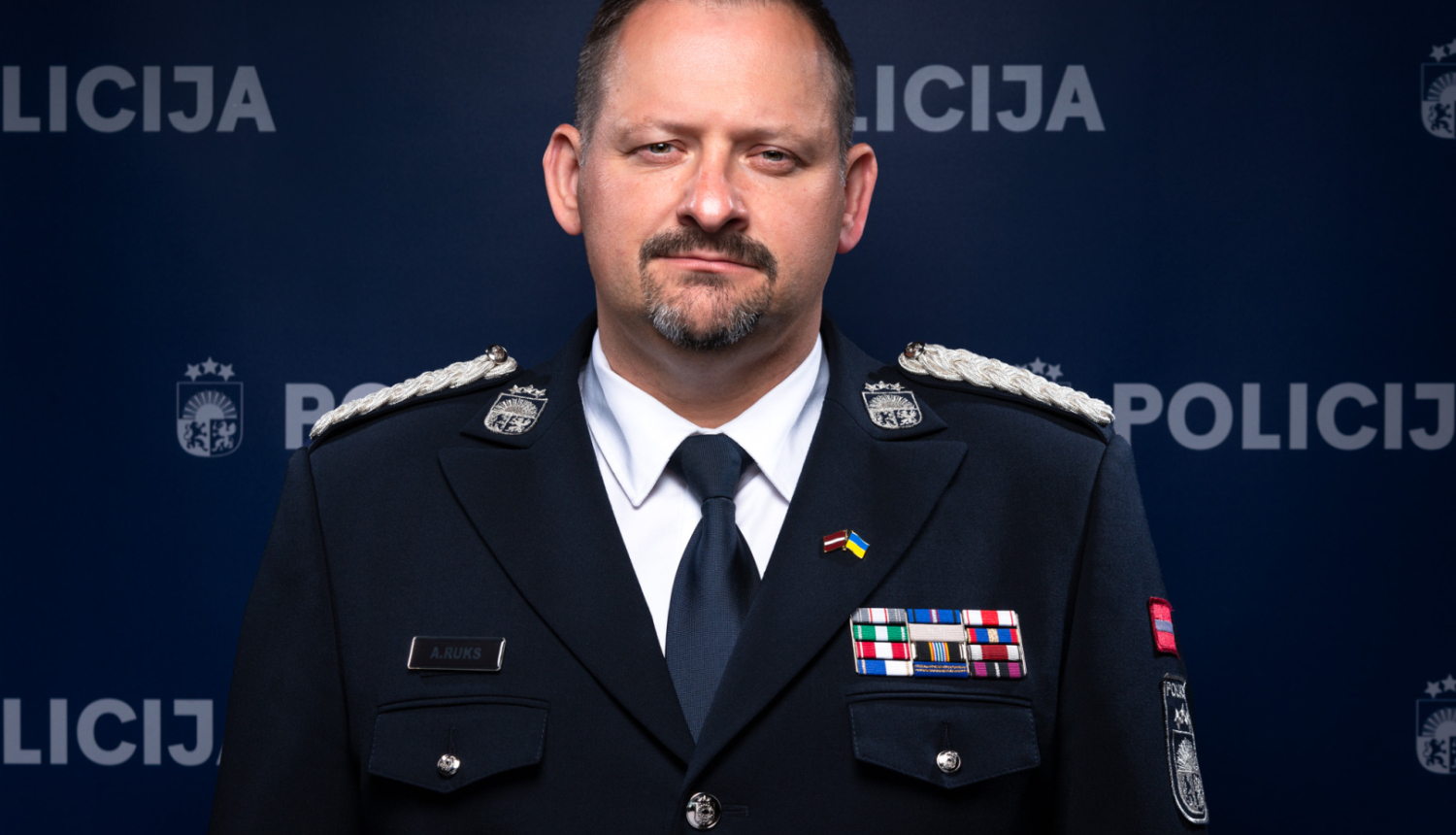 Policijas priekšnieks stāv pie Policijas banera