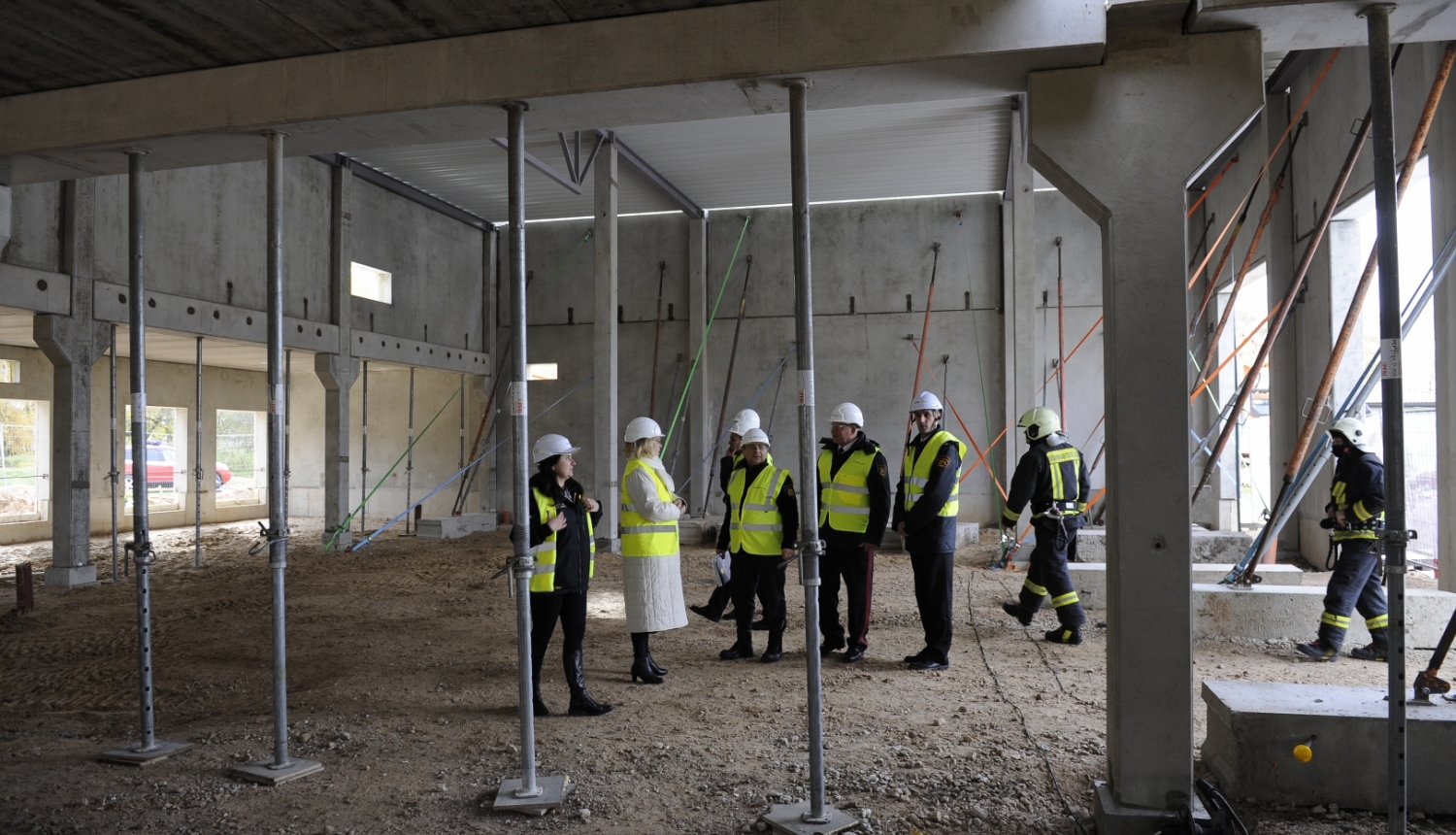 Ēkas iekšienē konstrukcijas un cilvēki ar zaļām vestēm