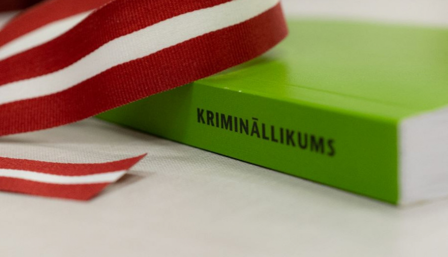 Zaļa grāmata uz galda ar Latvijas karoga lentīti