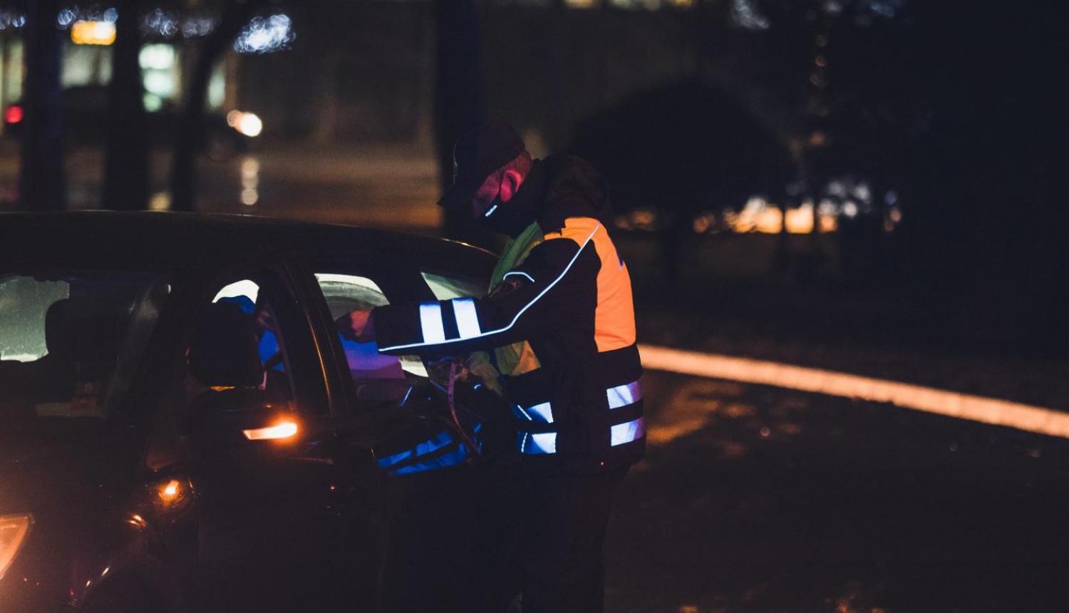policists pārbauda apliecinājumu automašīnas vadītājam
